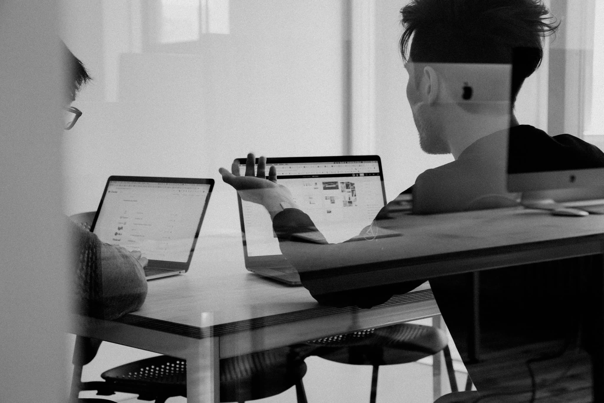 Two colleagues reviewing work together on laptops